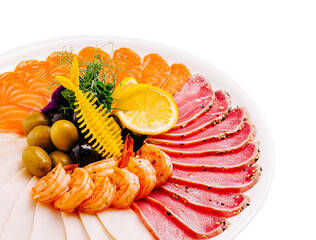 Sliced seafood platter with colorful fish and garnishes served on white dish