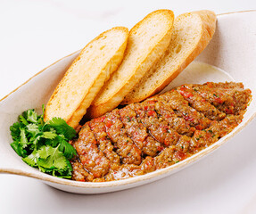 Traditional eggplant caviar made from roasted vegetables served with toasted bread slices and fresh cilantro on ceramic plate