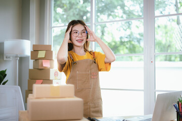 A young Asian female entrepreneur works from home, managing online sales, shipping parcels, marketing products, and ensuring client satisfaction efficiently.