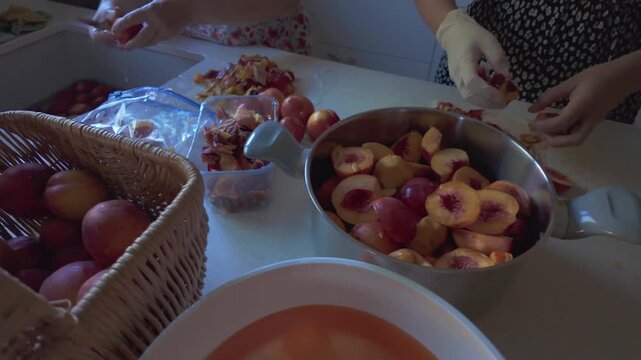 Pr&eacute;paration artisanale de confiture de nectarine, deux personnes qui coupent les fruits et les pr&eacute;parent