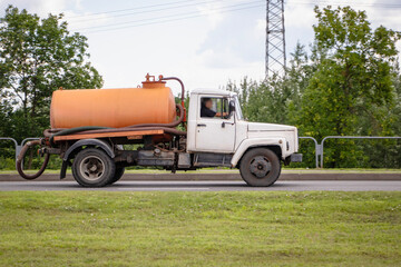 Truck transporting liquid waste along a rural road in daylight