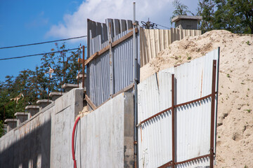 Construction site with sand pile and metal fencing in bright sunlight during the day