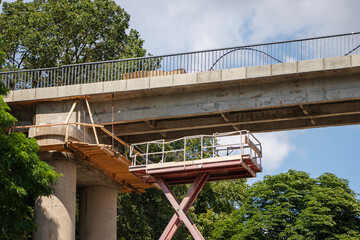 Construction progress on a bridge with scaffolding and trees in the background during daylight hours