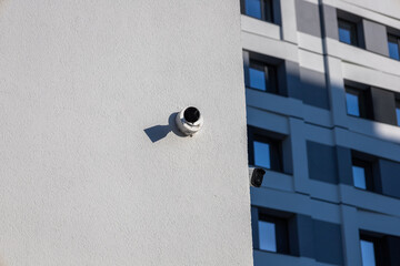 Two surveillance cameras are affixed to the walls of a contemporary building, highlighting urban...