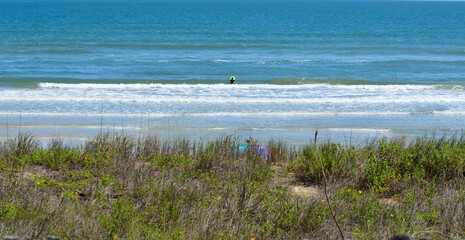 Ocean beach showing a surfer faraway.