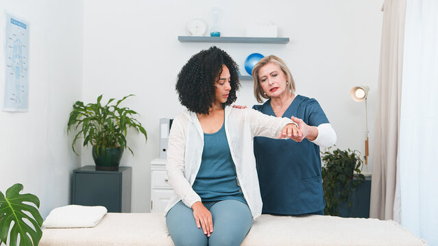 Experienced Senior Physiotherapist Providing Professional Arm and Shoulder Treatment to a Young Black Female Client