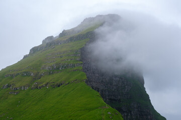 Towering green cliffs covered in lush vegetation extend skyward, shrouded in mist. Kallur...