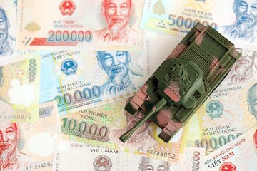 Vietnamese dong currency money bills and toy tank. The concept of army funds and weapons sales