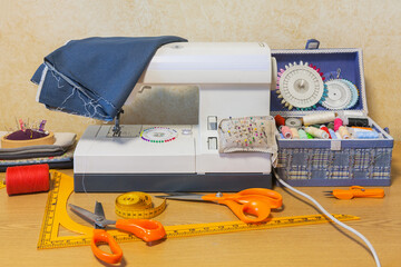 Workplace of a seamstress at home. Sewing machine, box with sewing supplies, accessories on the...