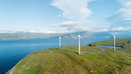 In the breathtaking Faroe Islands, towering wind turbines harness natural energy while overlooking...