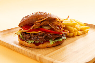 Burger with pulled beef, onion rings and fries.