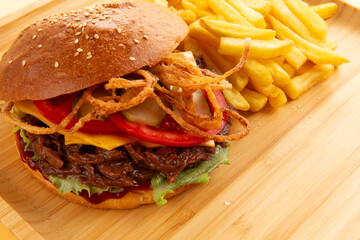 Burger with pulled beef, onion rings and fries.