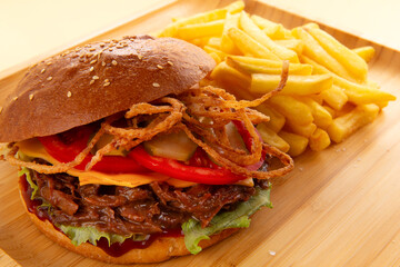 Burger with pulled beef, onion rings and fries.