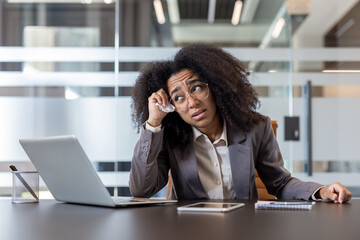 Tired African American young woman feeling unwell at workplace in office