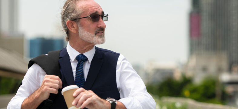 Senior businessman in a suit riding an electric skateboard in the city