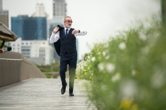 Senior businessman in a suit walking outdoors, checking the time on his watch - Powered by Adobe
