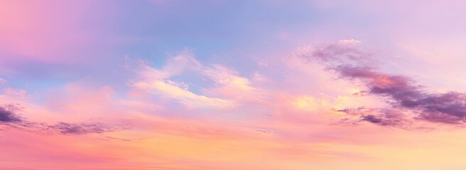 Fototapeta premium Sky with a soft pastel blend of pink, purple, and blue hues, illuminated by the golden light of sunrise or sunset, with wispy clouds scattered across the expansive canvas