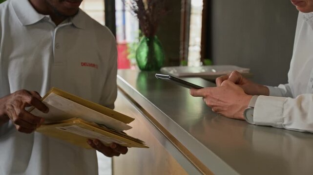 Close up of unrecognizable black courier giving tablet to unrecognizable woman nd starting choosing registered letter