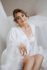 Elegant woman in white attire poses gracefully in soft light setting