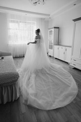 Bride in elegant gown preparing for wedding indoors in bright, airy room