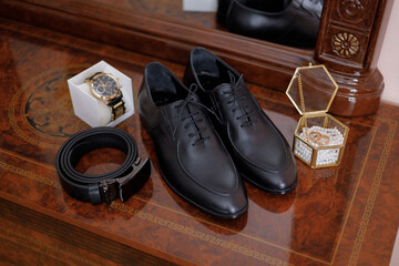Elegant black shoes and accessories displayed on a polished wooden surface in a stylish setting