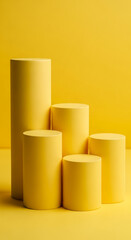 Fototapeta premium Five yellow cylinders of varying heights form a stepped display against a yellow background, ideal for product showcasing or minimalist design concepts