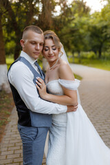Fototapeta premium Couple embraces tenderly in a park during golden hour on their wedding day