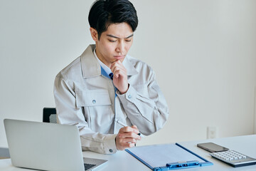 メモをとる作業服姿の日本人男性