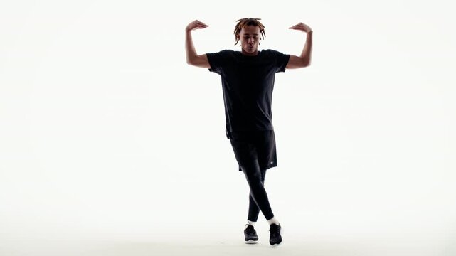 A young man with dreadlocks showcases dynamic and expressive street dance moves in a bright, high-key studio environment. His silhouette highlights artistic movement and passion.