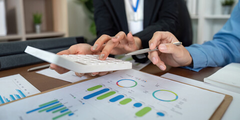Data Analysis. Team members using calculator and charts for financial planning in a corporate setting.
