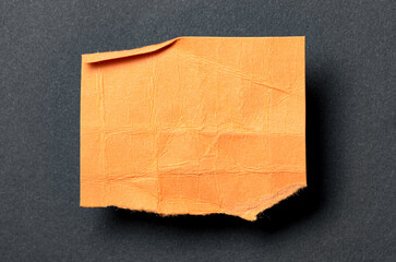 One single orange torn ripped wrinkled crumpled blank paper note with drop shadow, folded edge and...