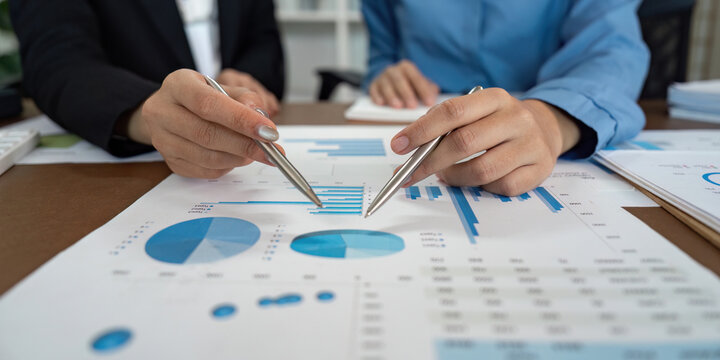 Collaborative Data Review. Professionals pointing at graphs and discussing insights in a business meeting. - Powered by Adobe