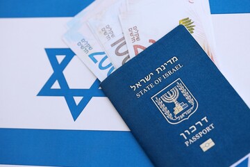 Israel New Shekels banknotes and passport on flag. The current Israel money bills and pass