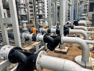 A row of industrial pumps, motors, and complex piping systems is captured in this image. The...