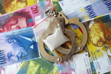 Swiss franc banknotes and cocaine pack with handcuffs. The current francs money bills and cuffs