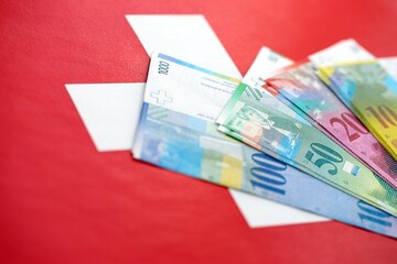 Swiss franc banknotes and flag. The current francs money bills lies on flag in big amount