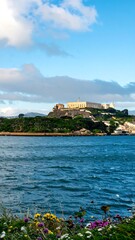 Naklejka premium Coastal fortress, cloudy sky, wildflowers