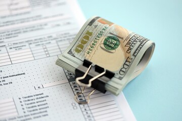 Big amount of United States USD dollar bills banknotes on table with 1040 tax return form
