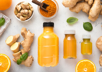 Ginger and orange energy shot immune drink with ginger root and turmeric powder on kitchen background.Top view.