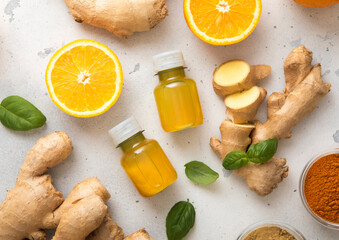 Immune turmeric energy shot drink with fresh raw ginger root and oranges on light background.Top view.
