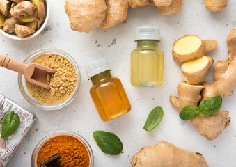 Bottles of immune turmeric ginger energy shot drink with fresh raw ginger roots and oranges fruits on light background.Top view.