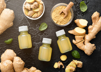 Bottles of immune ginger energy shot drink with ginger root and grounded powder on black background.Macro.