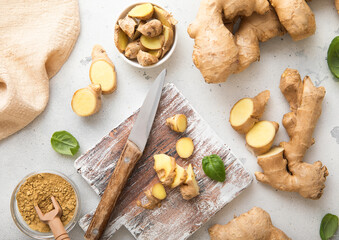 Raw fresh ginger root slices chopped with knife on wooden board with ginger powder on background.Top view.