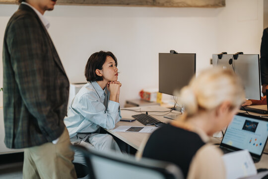 A group of diverse business professionals collaborating and thinking on a project in a stylish, rustic office setting focused on teamwork, productivity, and innovative solutions. - Powered by Adobe