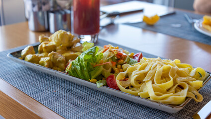 Delicious plate of pasta and vegetables served at a casual dining table in a bright setting
