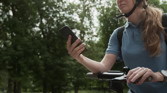 Close up of unrecognizable female courier holding smartphone and checking work pp trying to take new orders