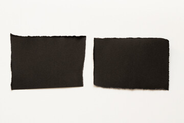 White background and two sheets of black paper with uneven, torn edges, which is used as a background, template or place for text