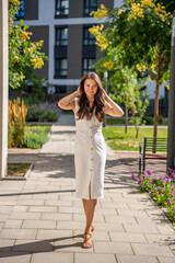 Young woman wearing a white midi dress walking outdoors in Old Money style. Concept of timeless fashion, graceful femininity and understated elegance in modern lifestyle.