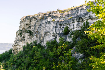 Majestic rocky cliff adorned with lush greenery, overlooking tranquil waters, showcasing natural beauty and serene landscape in a picturesque setting. Bakota bay, Dniester river, Ukraine