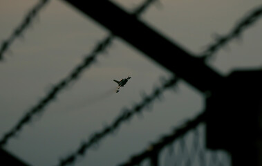Fighter jet in mid-air, performing a high-speed pass with smoke trails trailing behind it. The jet...